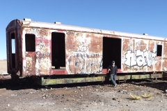 Christina Bergey in a train graveyard in Uyuni filled with train cars abandoned since the 1940s and rusting in the salty air.